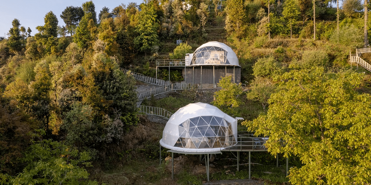 An image of two dome style separate bedroom and a pathway leading to one another amidst a lush garden
