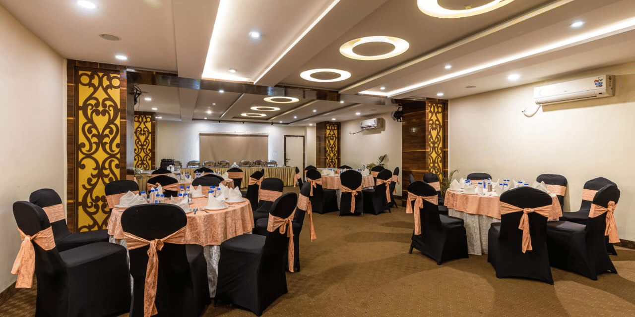 An extended view of Zodiac 1 gathering hall with bright lighting and sophisticated arrangement of chairs and tables at Papaya Tree Hotels.