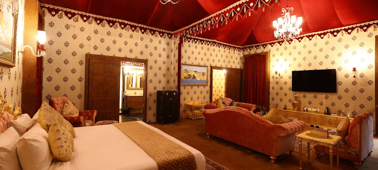 Image of a room with a bed and chandeliers hanging from the ceiling at Rajasthali Resort & Spa Jaipur.