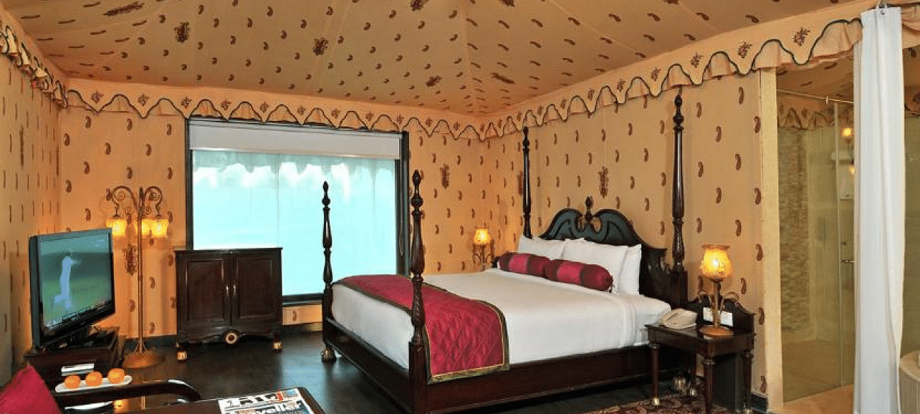 Side view of a room with a bed and a television in front of the bed at Rajasthali Resort & Spa Jaipur.