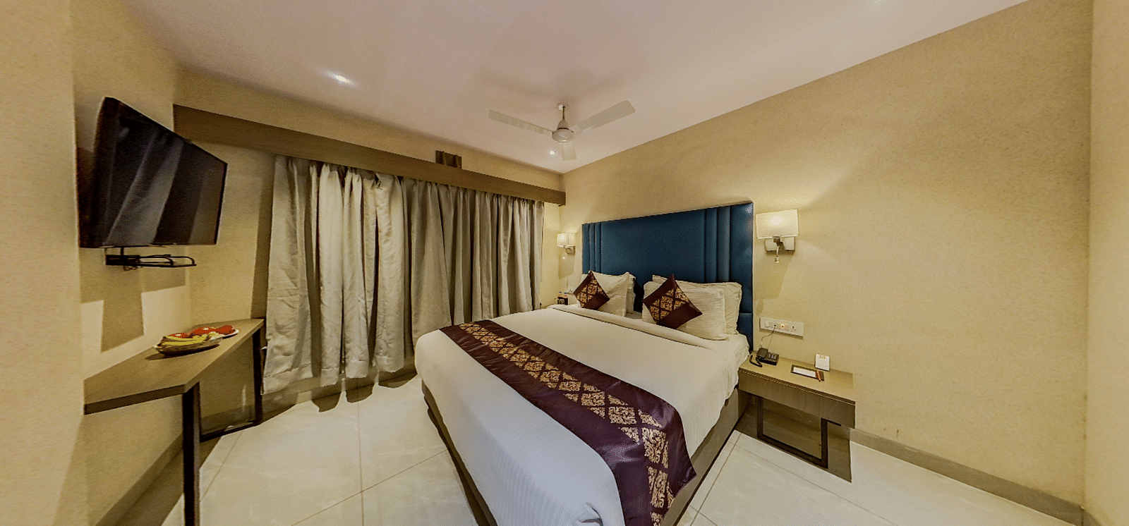 Luxurious double bed hotel room at Lords Eco Inn Dahej with blue headboard, modern amenities, flat-screen TV, and contemporary decor