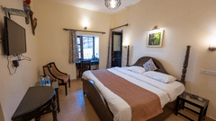 Side view of the standard room with a cosy bed and a TV mounted on the wall at The Pavilion, Nainital