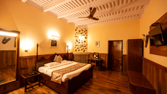 Oak Room features a large four-poster bed, wood-panelled walls, a beamed ceiling, and a mounted television at The Pavilion, Nainital