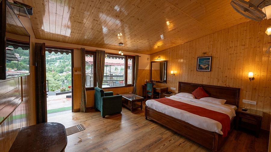 Spacious room with a cosy bed and chairs in Lake Facing Cottage at Himalaya Hotel, Nainital