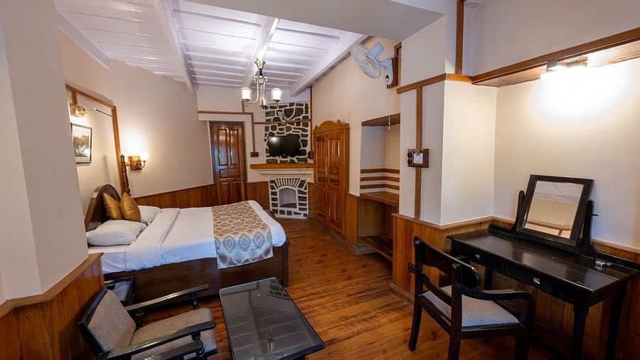 Side view of the Heritage Room with a cozy bed and seating in the corner at Himalaya Hotel, Nainital