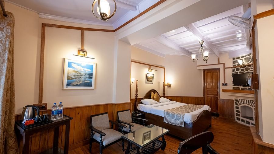 Side view of the Heritage Room with a cozy bed and seating in the corner at Himalaya Hotel, Nainital