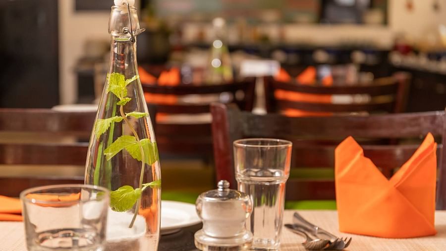 Glass  bottle and glasses along with an orange napkin at Kyriad Prestige Calangute, Goa