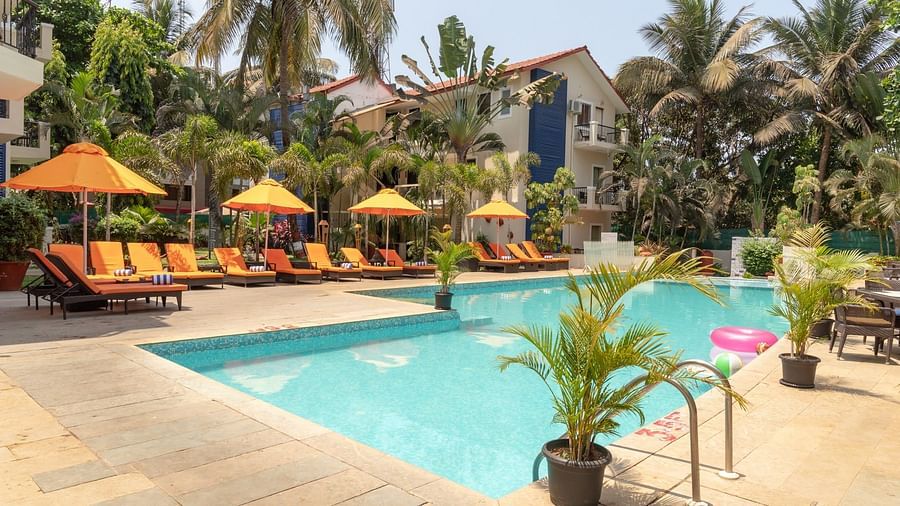 Swimming Pool at Kyriad Prestige Calangute, Goa surrounded by beach chairs