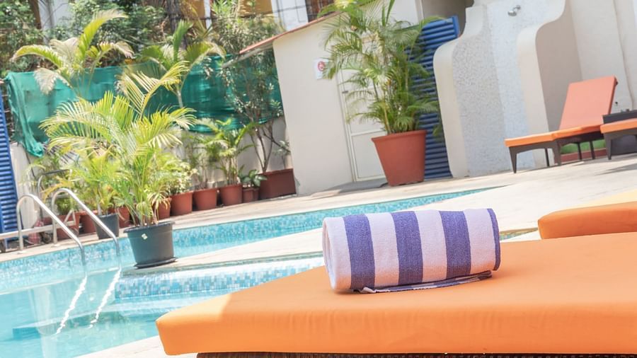 A striped towel on the beach chair besides the Swimming Pool at Kyriad Prestige Calangute, Goa