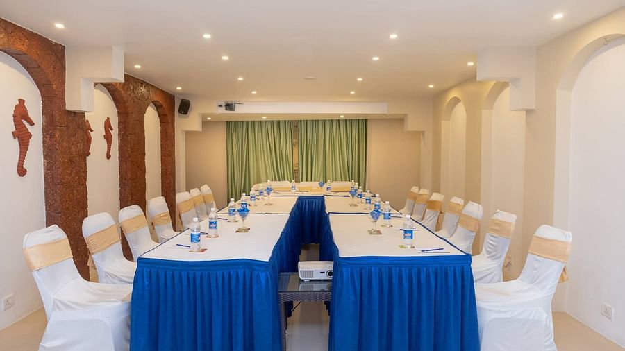 Two rows of White Chairs with tales in front at Opera Banquet Hall at Kyriad Prestige Calangute, Goa