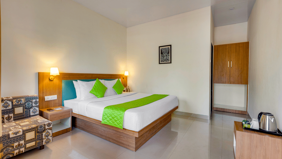 Full view of a bedroom with bed, seating, wardrobe area, and clean minimal interiors.