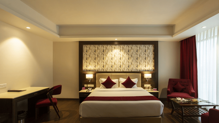 The bedroom of Sarovar Suite with a double bed, a lounge area by the window and a workspace with a table 