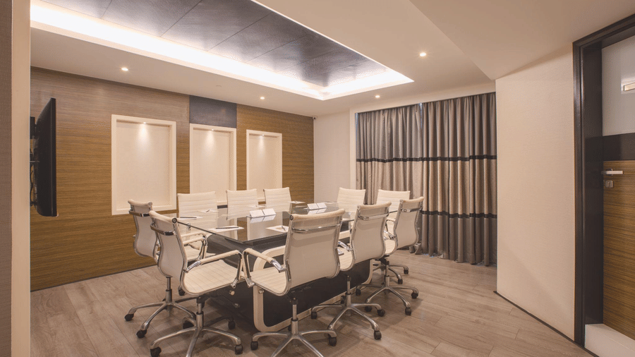 Professional conference room featuring a long boardroom table surrounded by white ergonomic office chairs.
