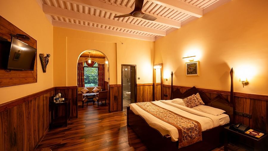 Oak Room features a large bed, wooden panelling, exposed ceiling beams, and an adjoining sitting area at The Pavilion, Nainital