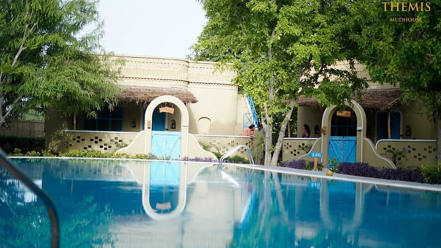 A pristine swimming pool surrounded by trees at Themis Mudhouse - A Nature's Retreat Resort & Wellnesss