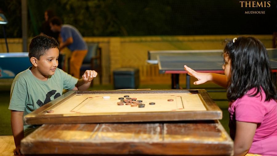 Two kids playing carrom at Themis Mudhouse - A Nature's Retreat Resort & Wellness