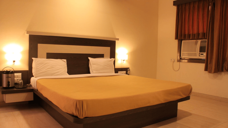 Cozy Deluxe bedroom with a large double bed, wooden headboard, side lamps, and dark window drapes.