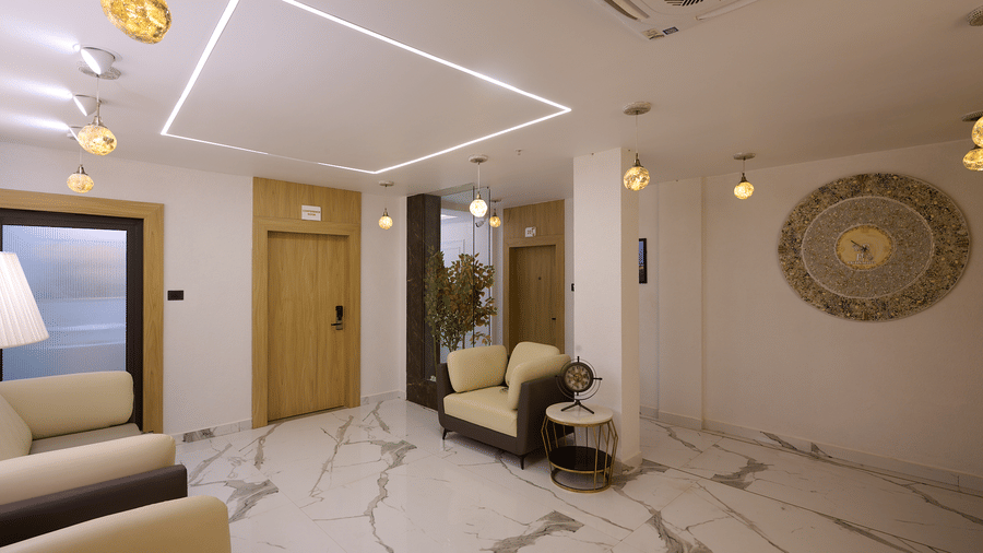 A hotel lobby or lounge area with white marble flooring, light-coloured walls, and a seating area | Voyage Eastin Suites