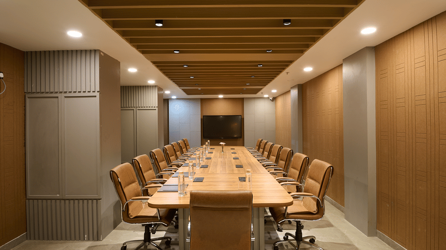A conference room with a long wooden table, multiple chairs, and wood-panelled walls and ceiling | Voyage Eastin Suites