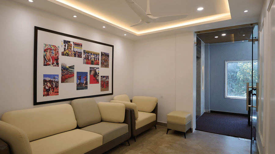 A hotel common area or lounge with light-coloured sofas, a photo collage on the wall, and glass doors leading to the outside | Voyage Eastin Suites