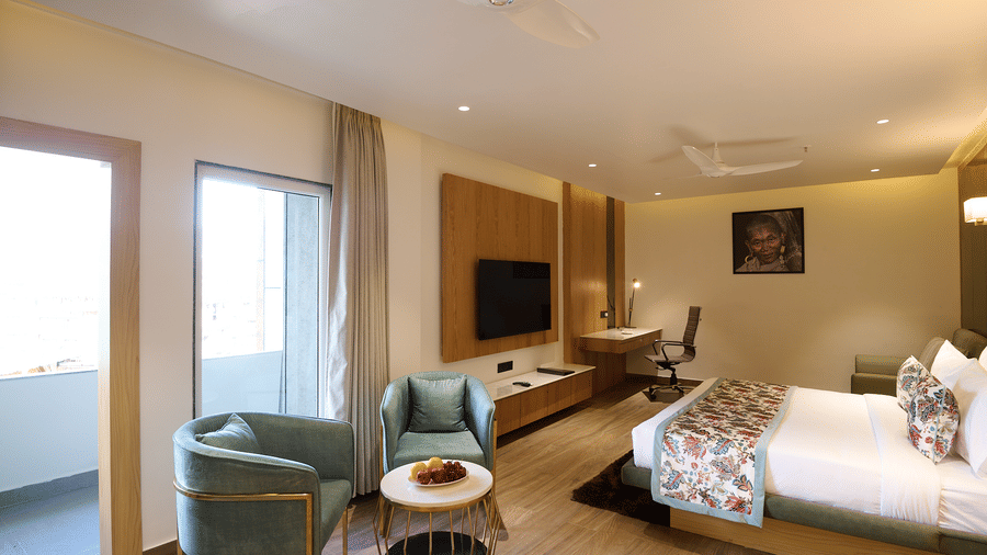 A hotel room with a double bed, a seating area with two armchairs and a small table, and a desk area next to the bed | Voyage Eastin Suites