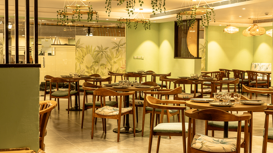 Restaurant interior with green walls, warm lighting and wooden tables and chairs at OJ Japanese Restaurant, Featherlite Evoma Hotel.