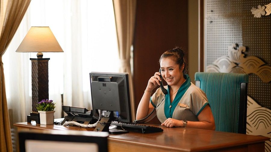 image of a receptionist attending to a call with a smile on her face - Maikhao Dream Villa Resort & Spa, Phuket