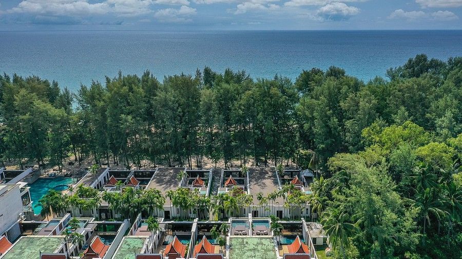 aerial view image of the maikhao dream villa resort and spa in phuket showcasing the the villas and the vast blue ocean separated by lush tropical greenery