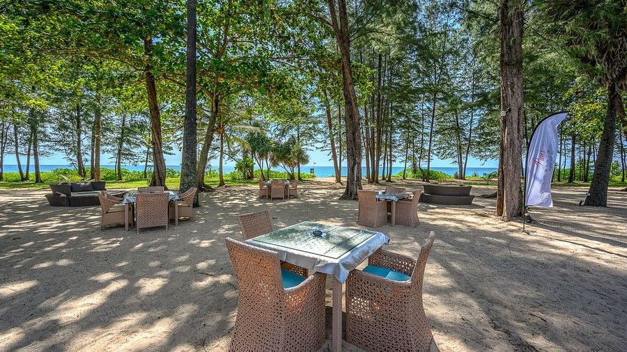image of several dining tables scattered on the beach overlooking the lush green canopy in the background - Maikhao Dream Villa Resort & Spa, Phuket 
