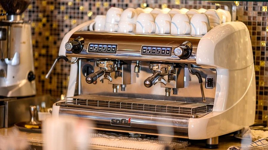 image of a coffee machine with several white coloured coffee mugs lined together