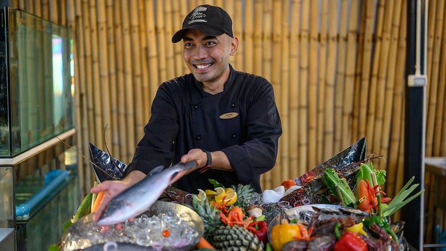 image of a person smiling as he demonstrates a fish at maikhao dream villa resort and spa, phuket