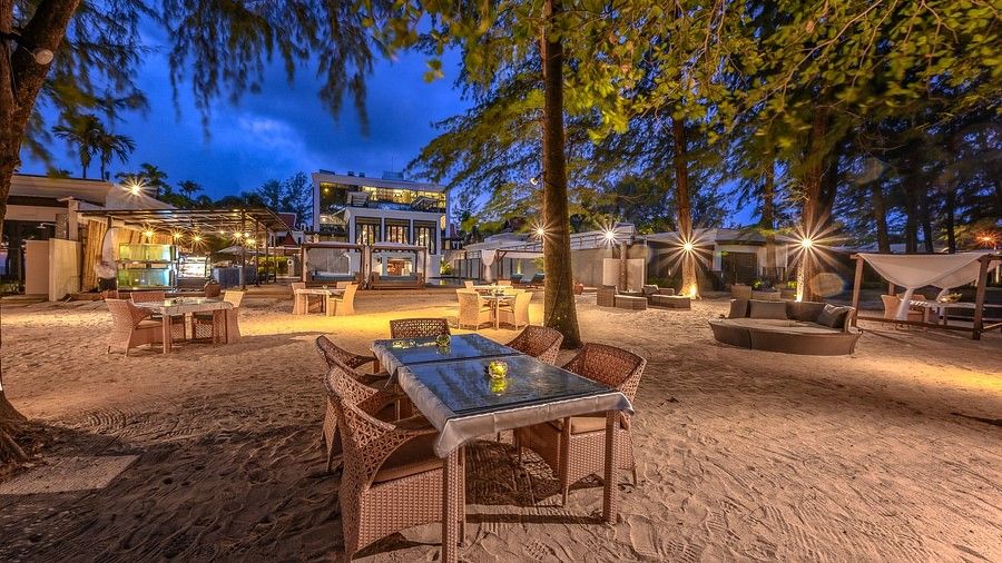 a close up image of a dining table with four chairs on a late evening - Maikhao Dream Villa Resort & Spa, Phuket