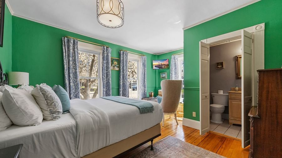 A bedroom with , green walls, and large windows lat Hartstone Inn.