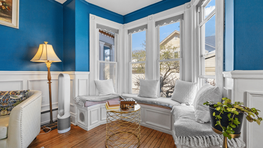 A window seating area at Hartstone Inn, featuring white furnishings, teal walls and fresh flowers