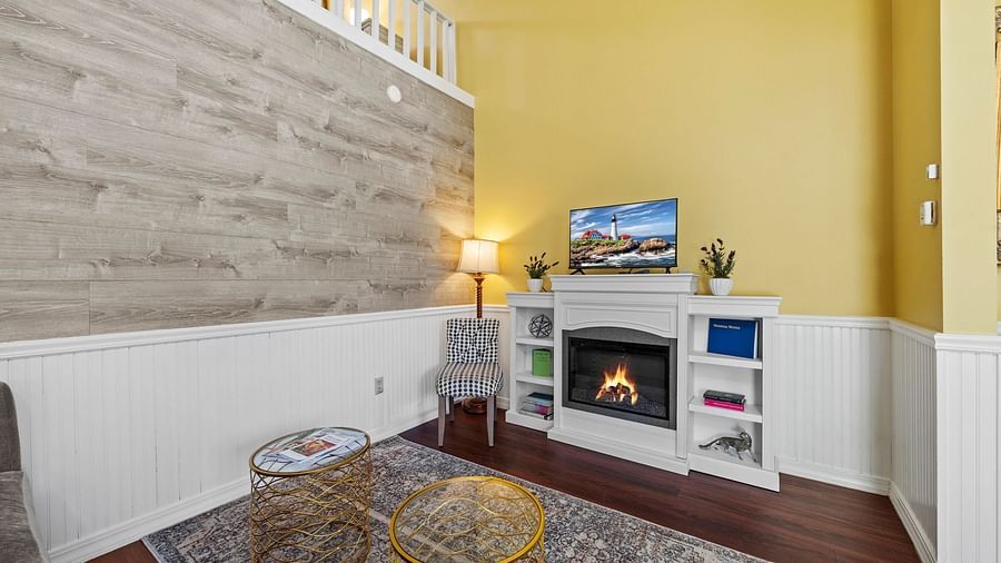 Cosy indoor lounge at Hartstone Inn with yellow walls, a fireplace, a gray armchair, and a staircase
