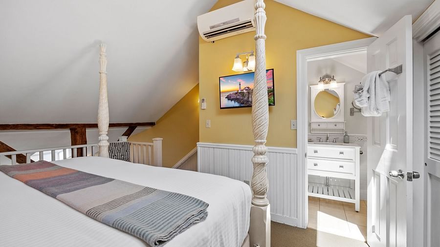 A room with double bed, Ac, tv and warm yellow accent walls at Hartstone Inn