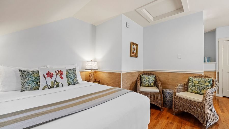 A room with bed, white walls, and floral themed pillows at Hartstone Inn.