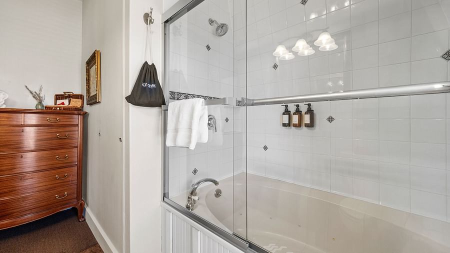 White bathroom with bath tub combo and mounted toiletry dispensers at Hartstone Inn.
