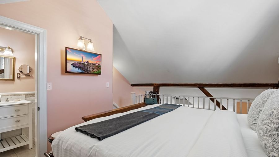 A room with sloped ceiling, compact vanity, and neutral decor at Hartstone Inn