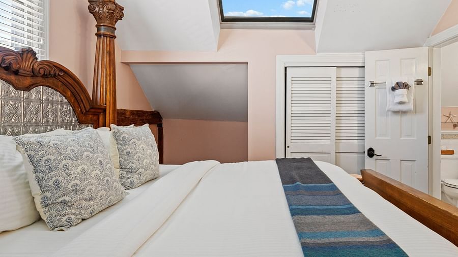 A bedroom with skylight, wicker headboard, and pastel walls at Hartstone Inn