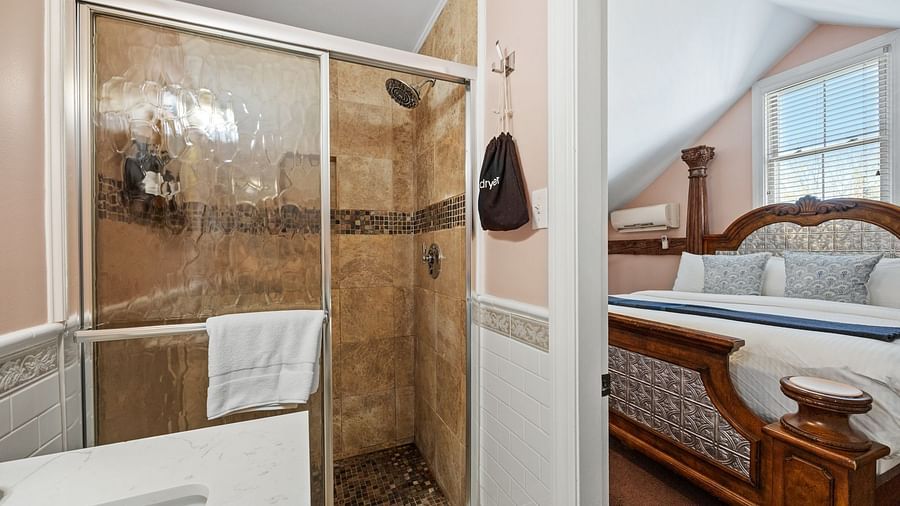 A room with separate shower area, hanging towels, a queen sized bed at Hartstone Inn.