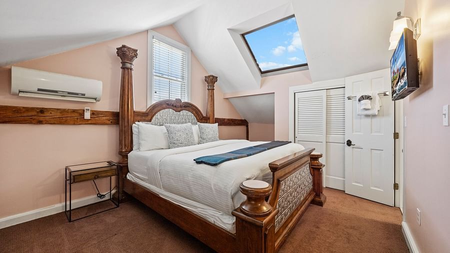 A bedroom with four-poster bed, flat screen TV, and traditional furnishings at Hartstone Inn