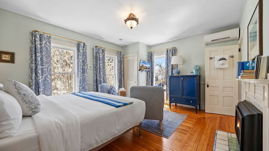 A air conditioned room with queen size bed and floral curtains at Hartstone Inn