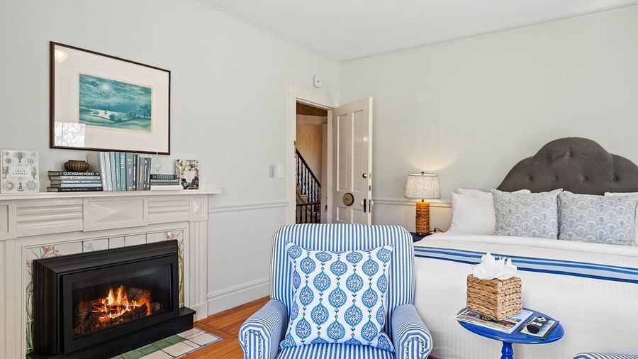 Bedroom with fireplace, two armchairs, and bed at Hartstone Inn.