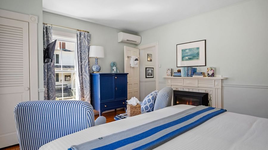 Guest room with a table, armchairs, and bed with blue-striped runner at Hartstone Inn