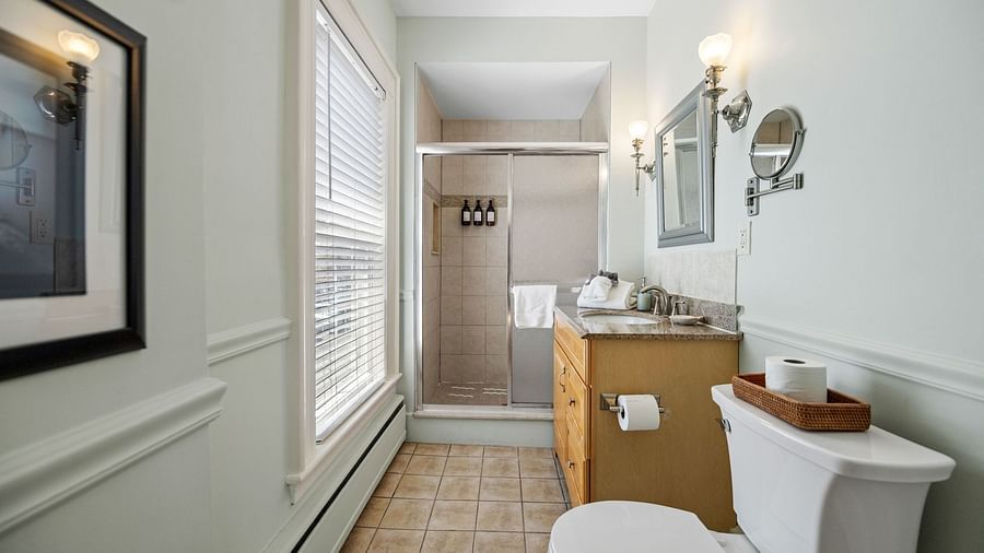 Narrow bathroom with sink, toilet, a small shower area and wall mirror at Hartstone Inn