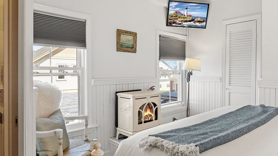 Room with fireplace, modern chair, and TV mounted above at Hartstone Inn