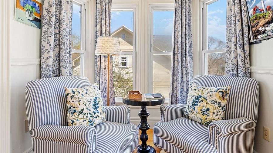 Two striped chairs and a table by large windows at Hartstone Inn