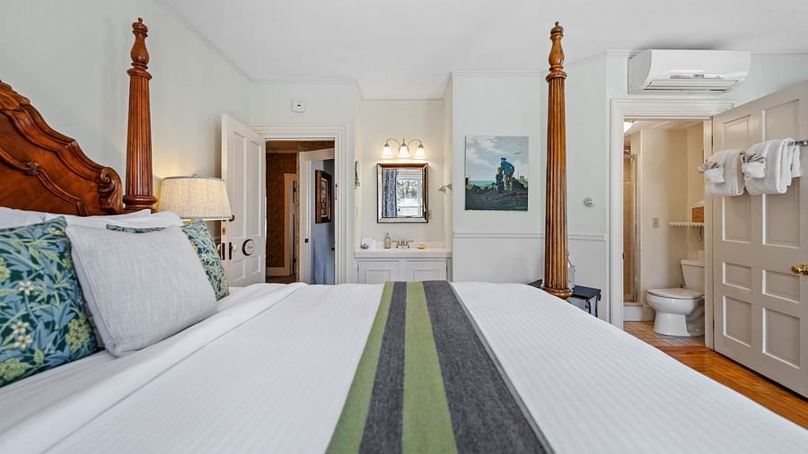 Spacious bedroom with wooden four-poster bed and green runner at Hartstone Inn.