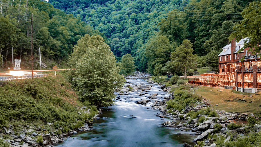a beautiful river flowing over a rocky stream in front of the resort with a beautiful mountain vistas in the background - Historic Tapoco Lodge